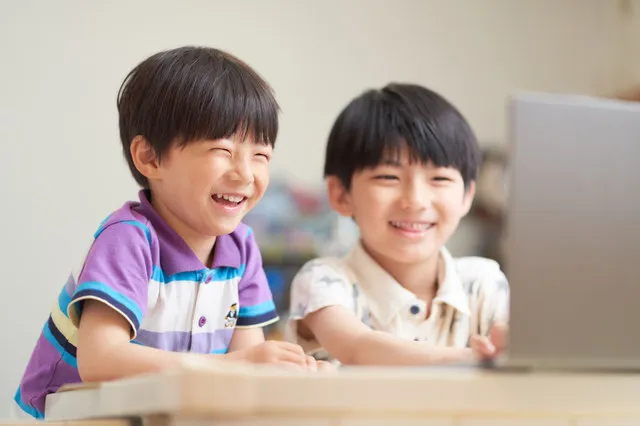小学生男子が笑顔でパソコンを見ている画像